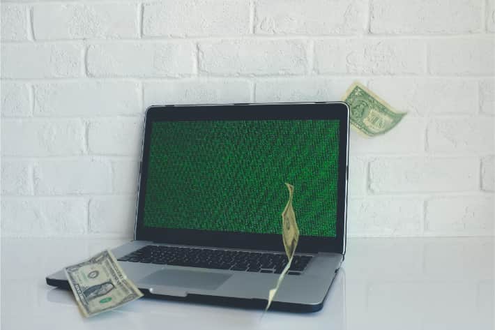 Laptop hackeado com notas de dólares caindo