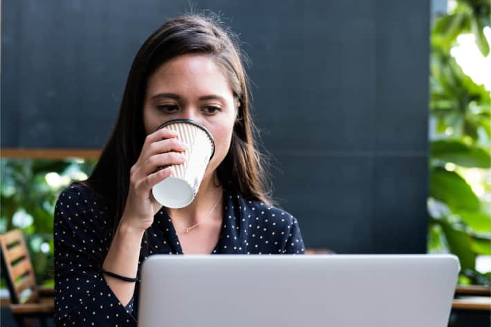 Mulher navegando no laptop e bebendo café