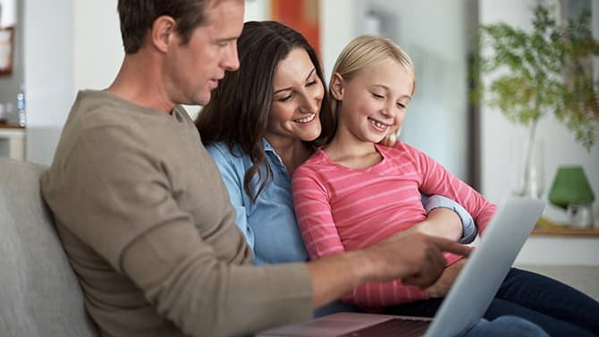 Um blog particular pode impedir que estranhos saibam detalhes pessoais sobre a sua família. A imagem mostra dois pais e sua filha sentados em um sofá, olhando juntos para um dispositivo tablet.